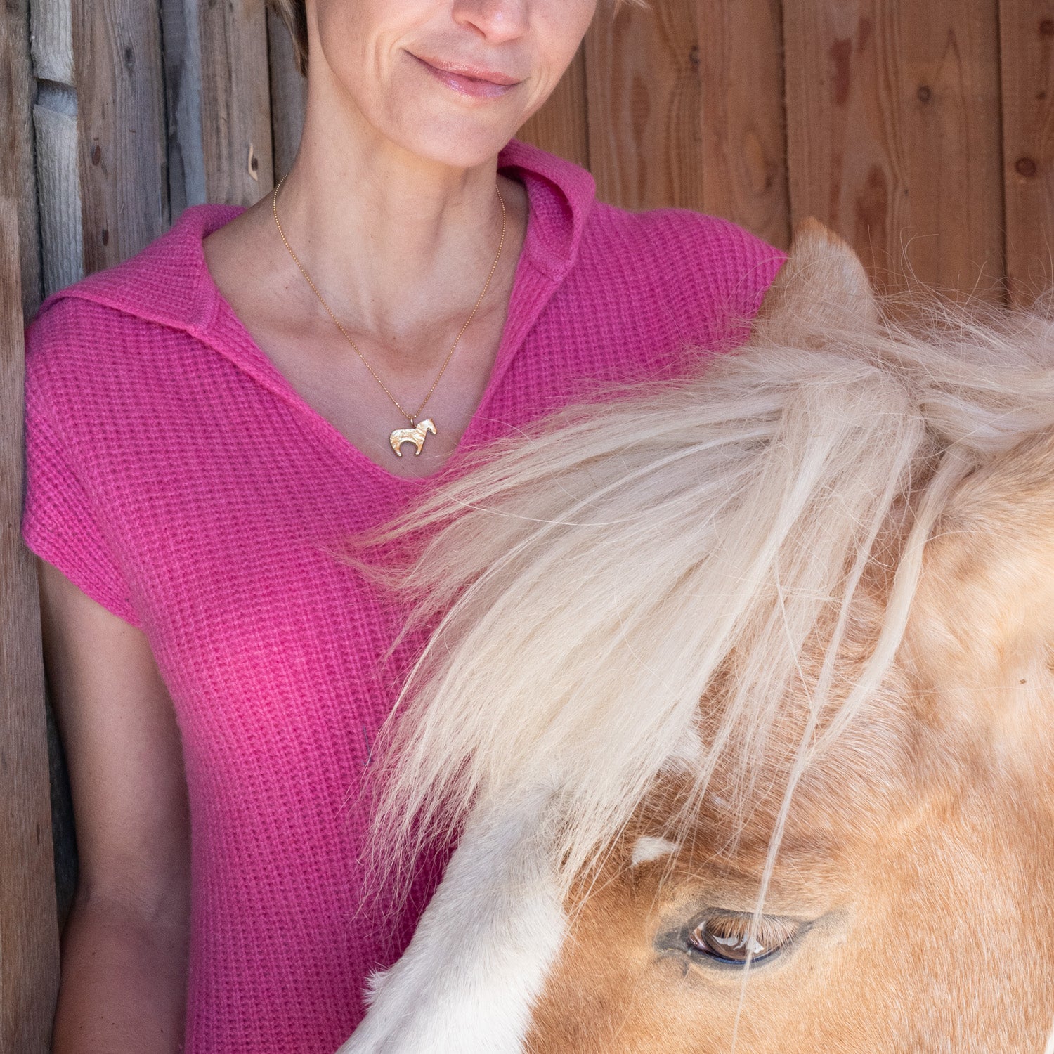 Firehorse pendant in bright yellow bronze worn by model next to a horse — Zefiro Jewels